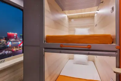 Capsule pod room night upper lower bunk open city view GettSleep Aeroexpress hotel