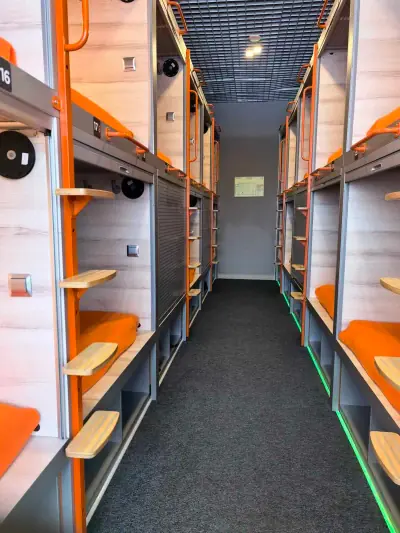 Corredor cápsulas dobles iluminación LED verde suelo hotel aeropuerto GettSleep Aeroexpress