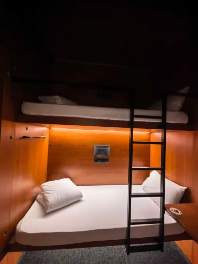 Vista general interior habitación cupé GettSleep cama albornoz estante zona ducha Terminal C