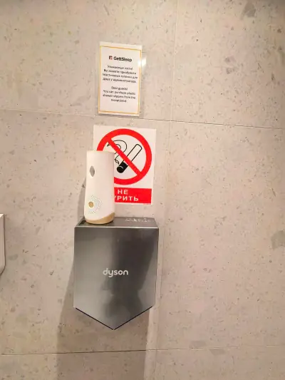 Baño compartido GettSleep secador Dyson aviso no fumar pared madera Terminal C