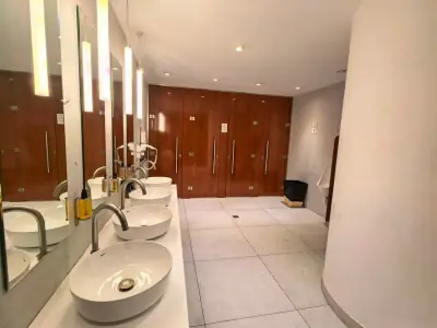 Primer plano ducha baño compartido GettSleep grifo cromo dispensador champú pared madera Terminal C