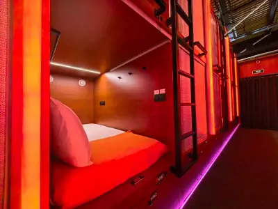 GettSleep 솔로 포드 캡슐 넓은 내부 뷰 오렌지 침구 따뜻한 목재 조명 C터미널