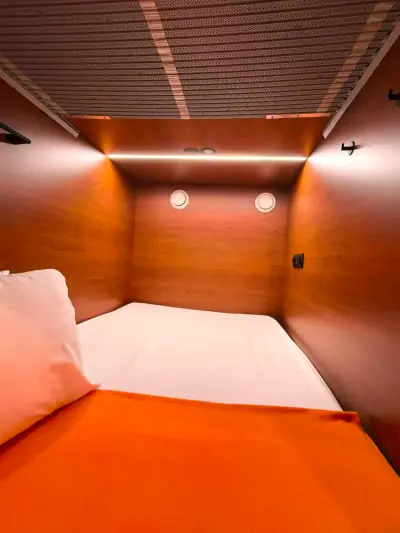 Cápsula superior pod doble GettSleep abierta ropa naranja almohada escalera Terminal C