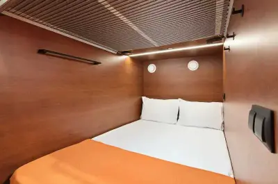 Vista interior completa cápsula superior doble GettSleep ropa blanca madera cálida Terminal C