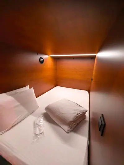 Ducha privada minihabitación Yin-Yang GettSleep alcachofa lluvia paredes madera cálidas Terminal C