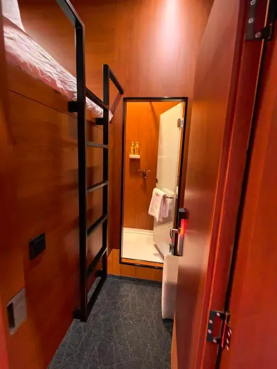 Cama cápsula superior Yin-Yang GettSleep almohadas blancas ropa naranja artículos estante Terminal C