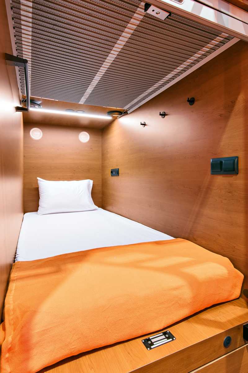 Detailed interior of lower single capsule with cozy bed and storage at Sheremetyevo Terminal C