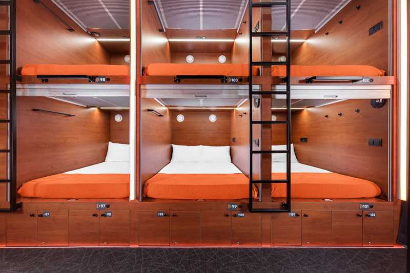 Interior of lower double capsule featuring comfortable beds, lighting, and charging ports at Terminal C